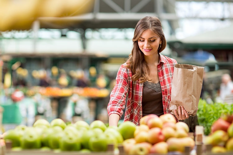 Woman at a grocery store, grabbing apples.